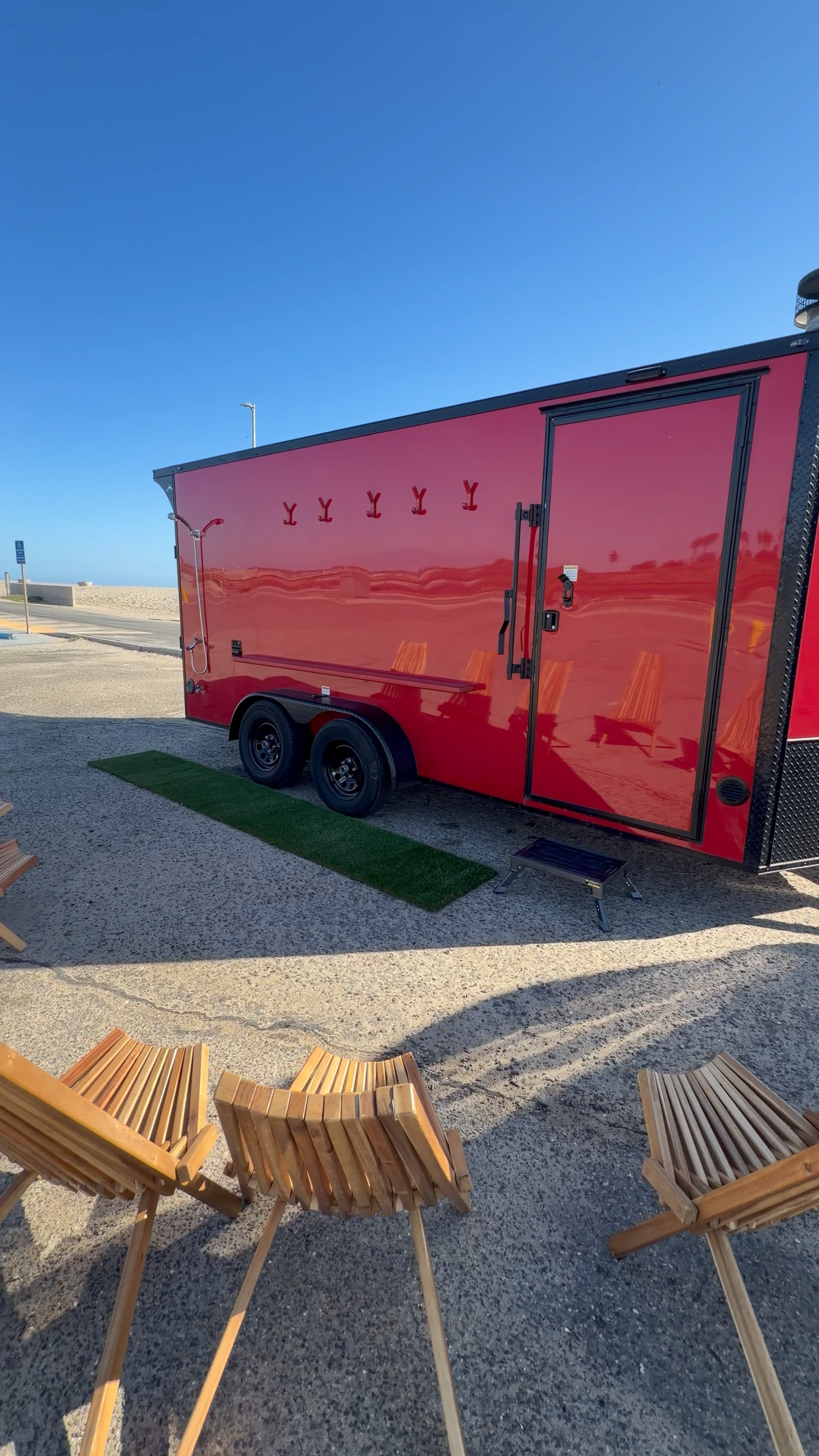 Red mobile sauna trailer set up near the beach